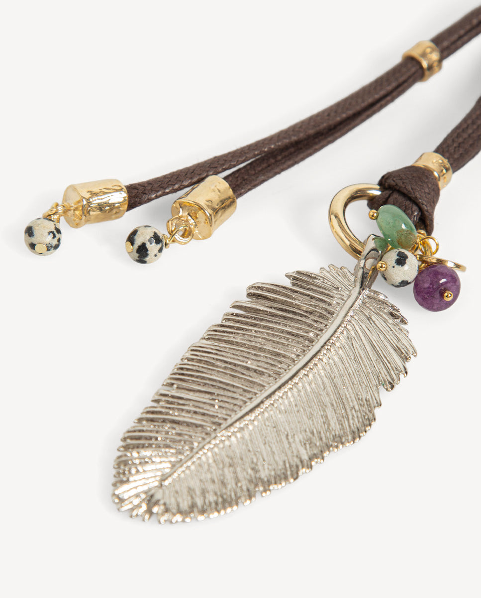 Detalle del collar Nervia marrón de Emolo con colgante de hoja plateada, cuentas verde y morada y cordones marrones