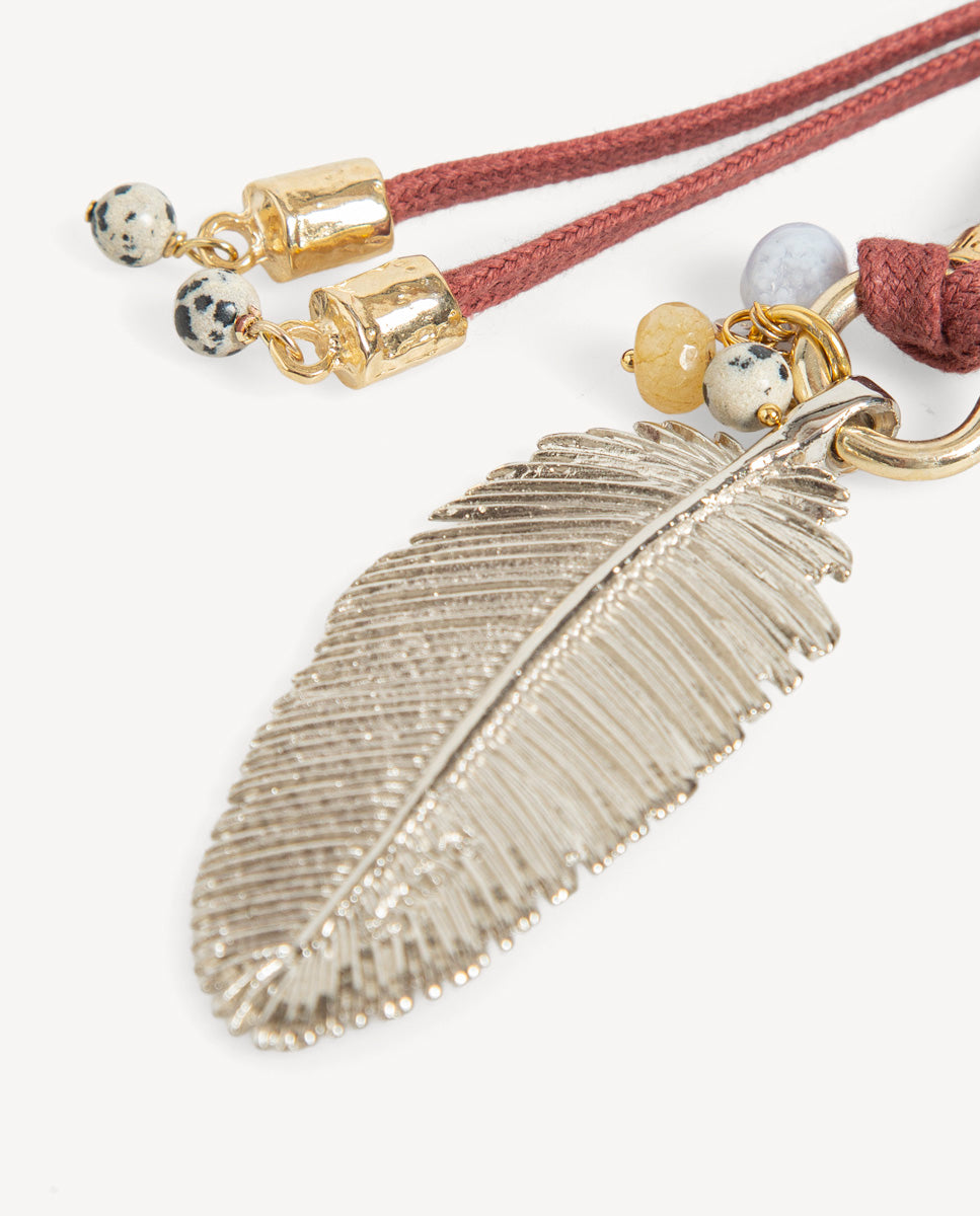 Detalle del collar Nervia burdeos de Emolo con colgante de hoja plateada, pequeñas cuentas y cordones burdeos