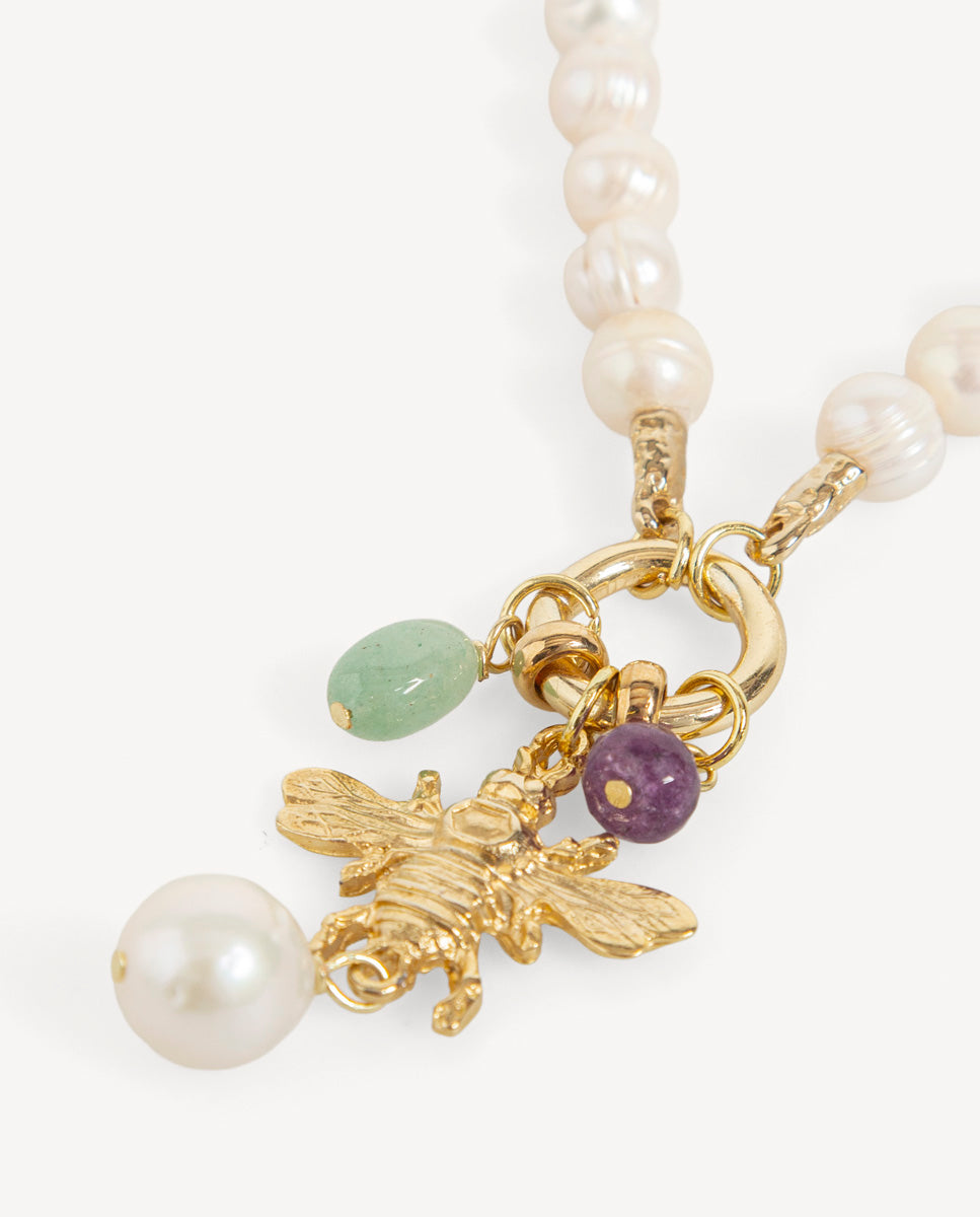Detalle del collar Bimett de perlas de Emolo con colgante de abeja dorada, perla blanca y cuentas verde y morada