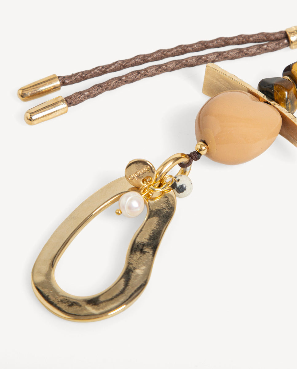 Detalle del collar Hanner camel de Emolo con colgante dorado de gota calada, cuenta color miel y pequeñas cuentas blancas