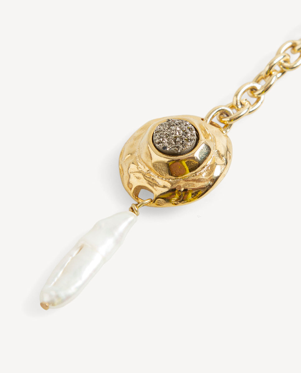 Detalle del collar largo Solmara de Emolo con drusa circular sobre medallón dorado y perla blanca alargada colgante