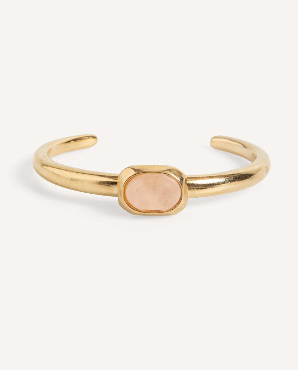 Brazalete abierto Luvo de Emolo en tono dorado con cuarzo rosa ovalado en el centro