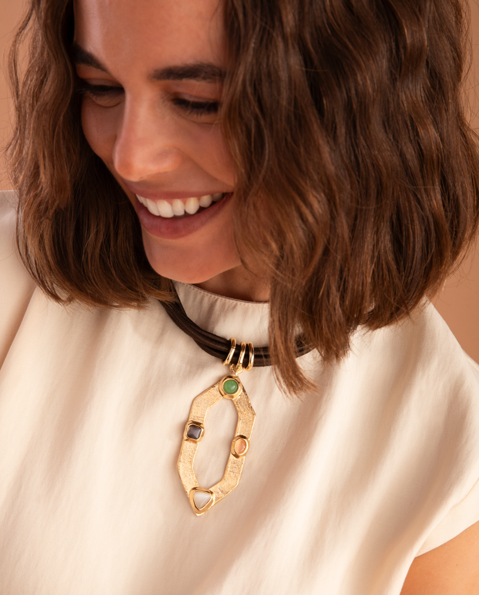 Modelo con collar corto de Émolo de varios cordones marrones y colgante geométrico dorado con piedras de colores