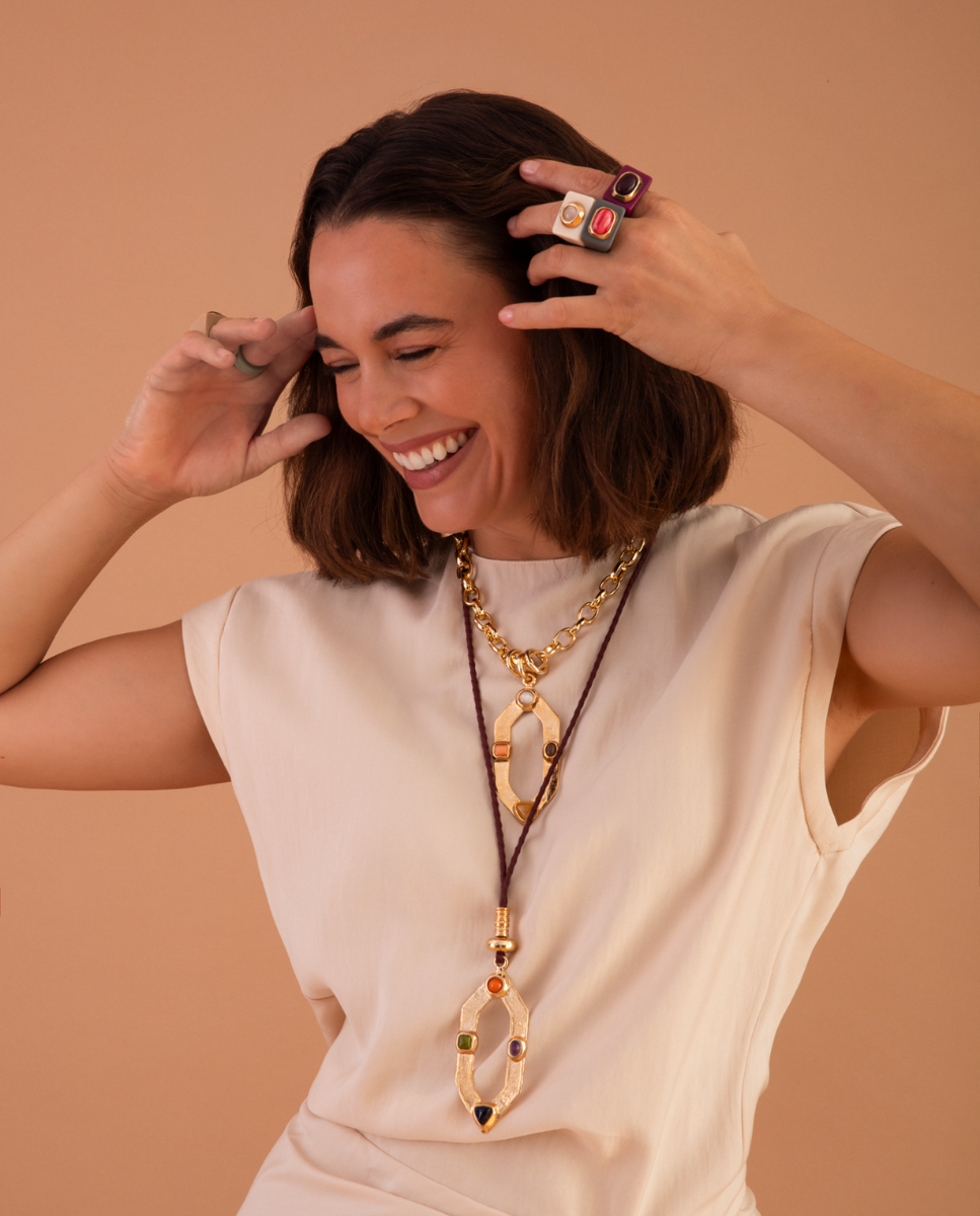 Modelo con dos collares de Émolo de distinta longitud, con colgantes geométricos dorados y piedras de colores