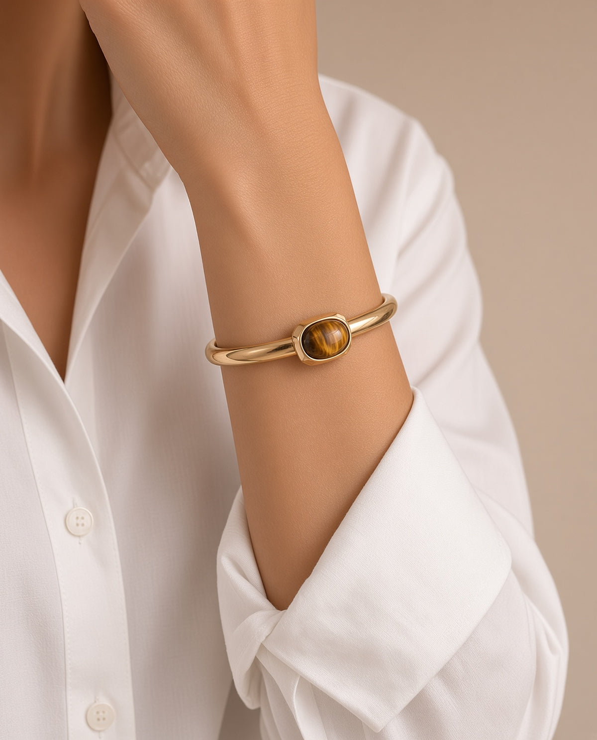 Detalle del brazalete Luvo de Emolo en dorado con ojo de tigre puesto en la muñeca