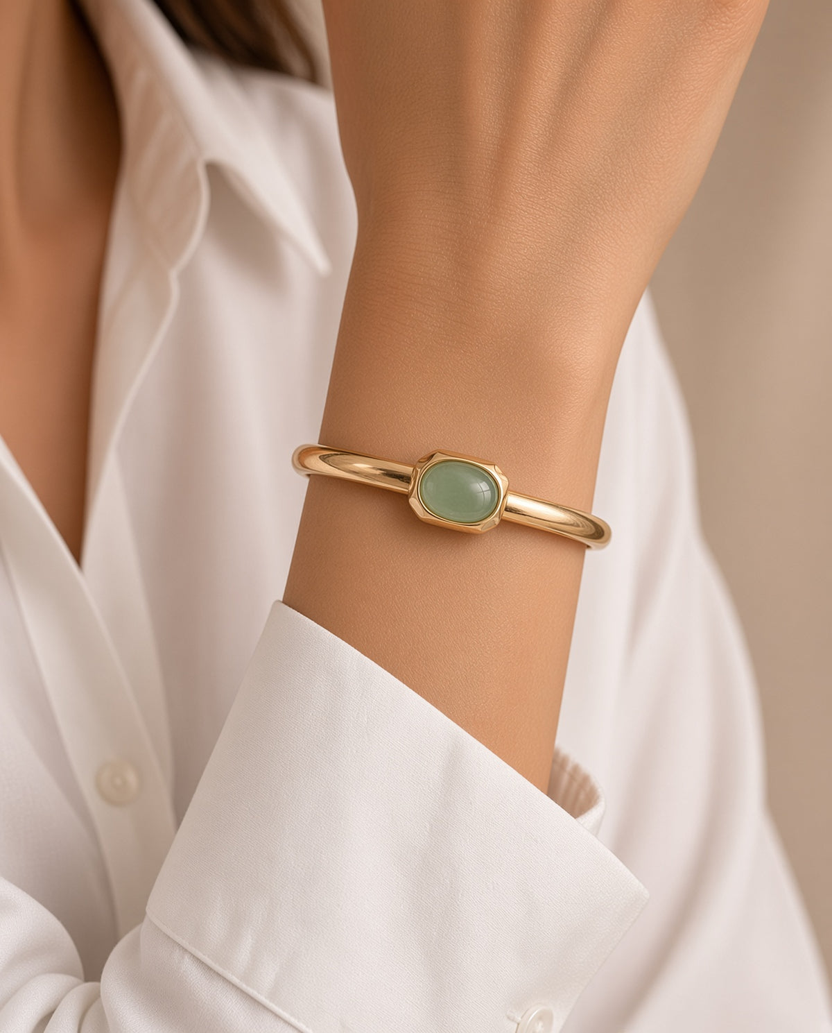 Modelo con el brazalete Luvo de Emolo en dorado con aventurina verde, sobre camisa blanca