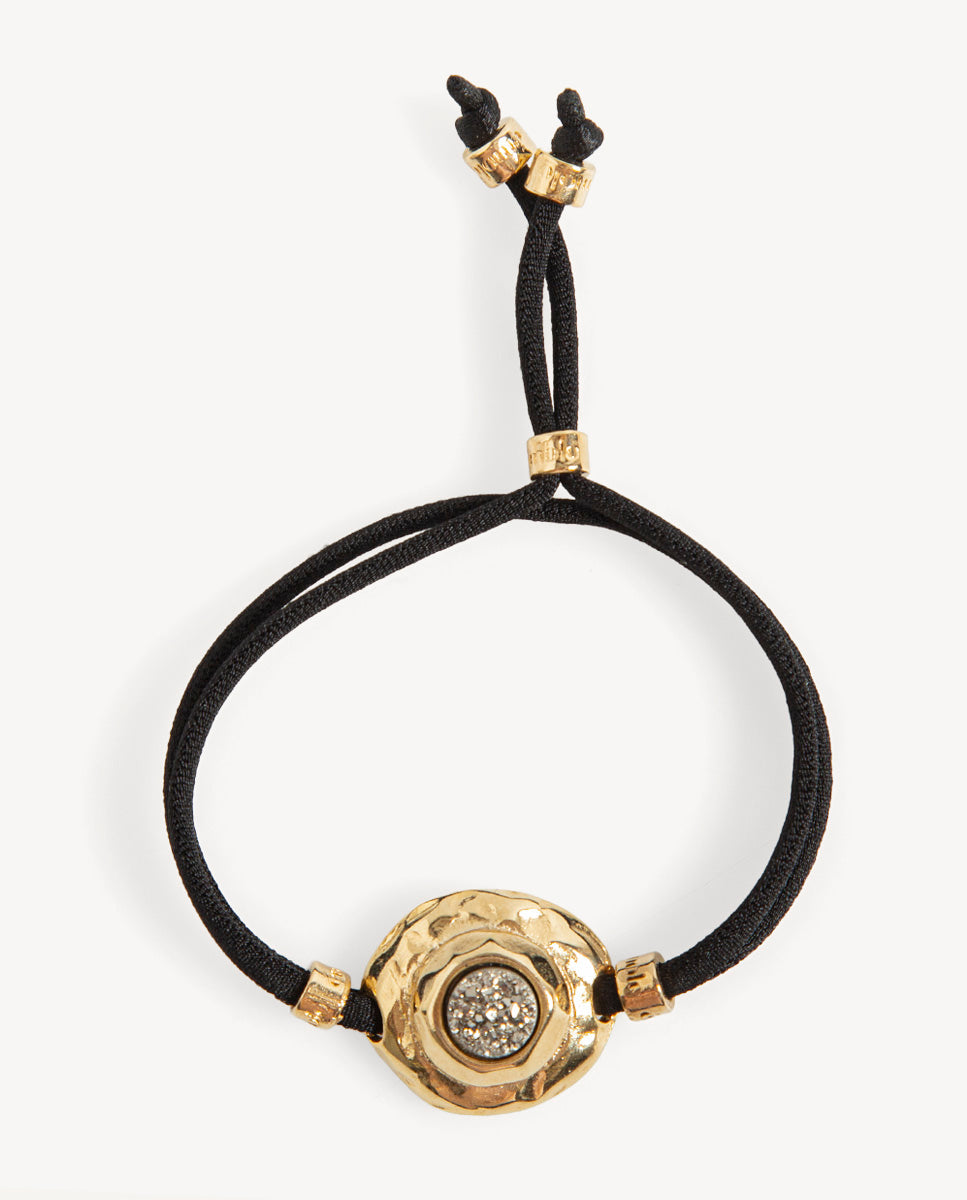 Pulsera Solmara de Emolo con cordón negro ajustable y medallón dorado texturizado con drusa circular color titanio