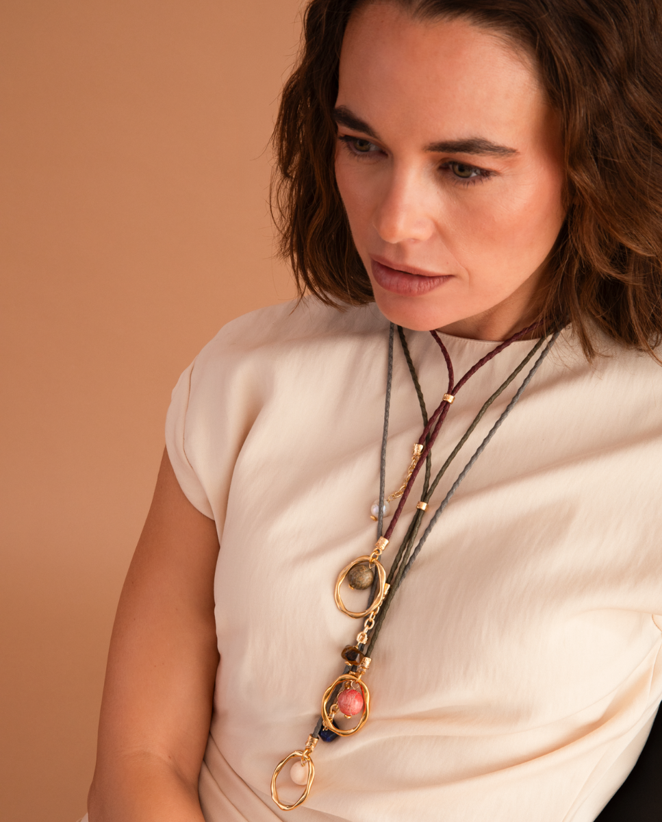 Modelo con collares largos de Emolo de cordón gris y marrón, aros dorados y cuentas de colores