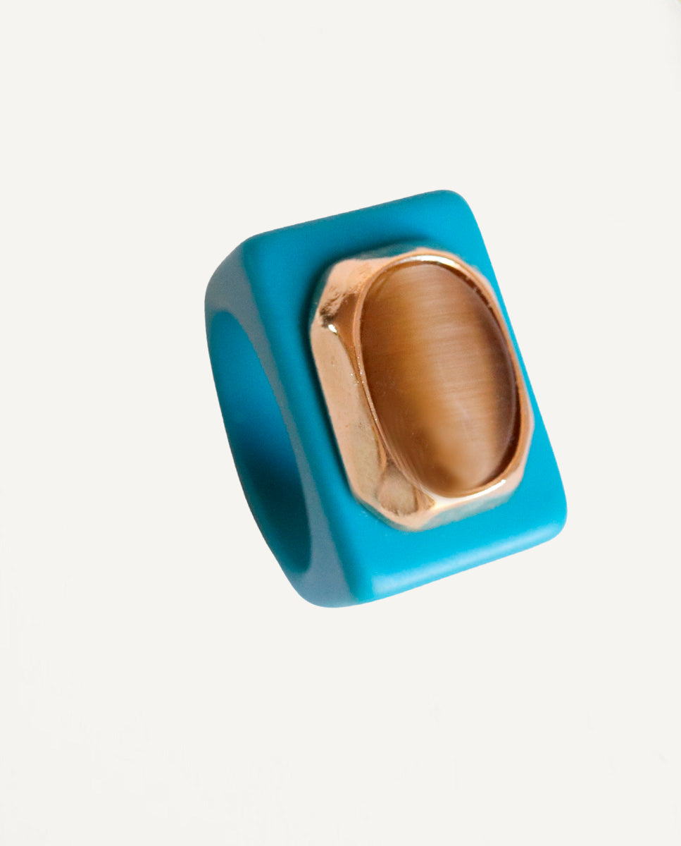 Anillo Émolo en azul océano con selenita fumé de talla ovalada XXL y engaste dorado, vista frontal sobre fondo claro