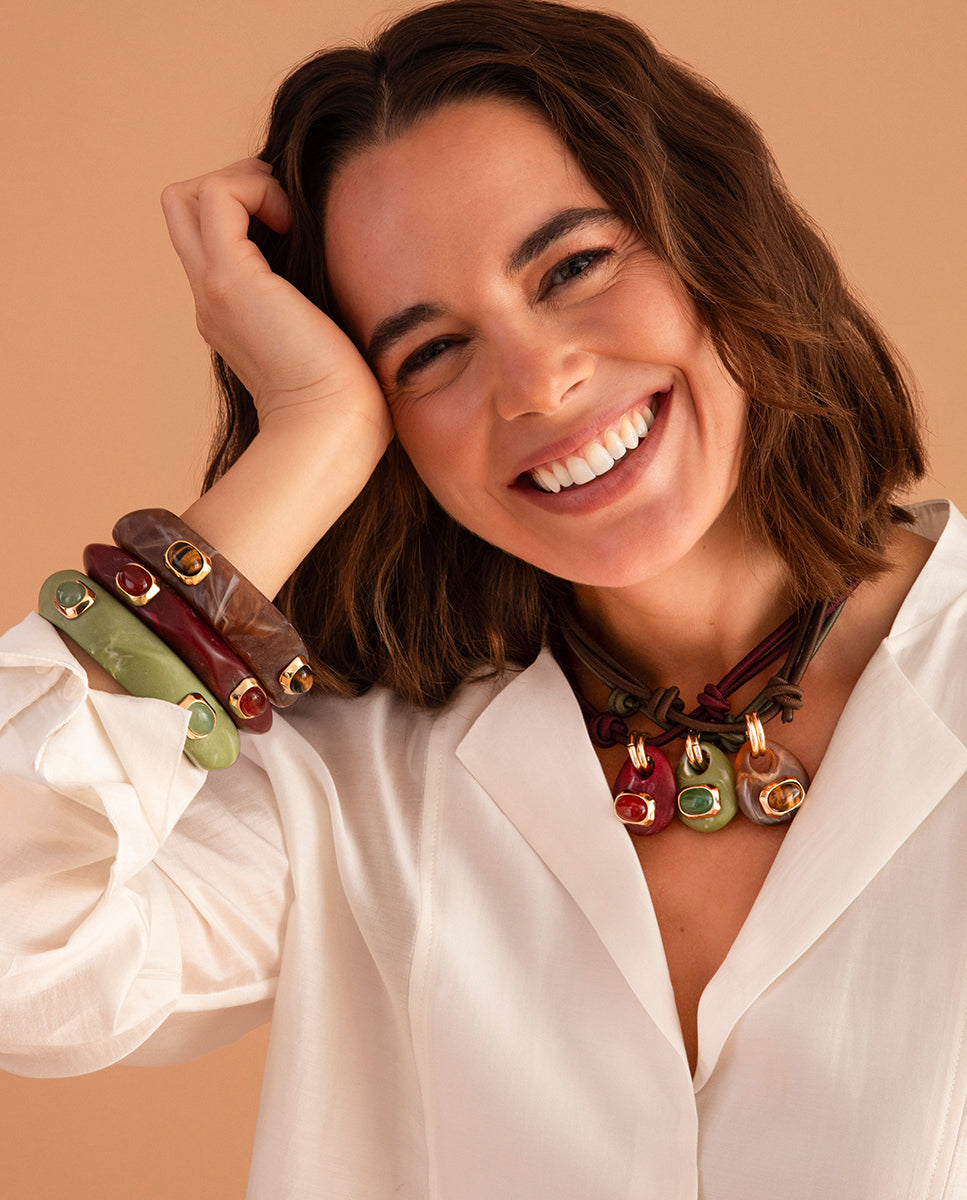 Modelo con la mano en el pelo luciendo varios collares cortos Milu Sianna mármol de Emolo en tonos rojo, verde y amarillo sobre camisa blanca