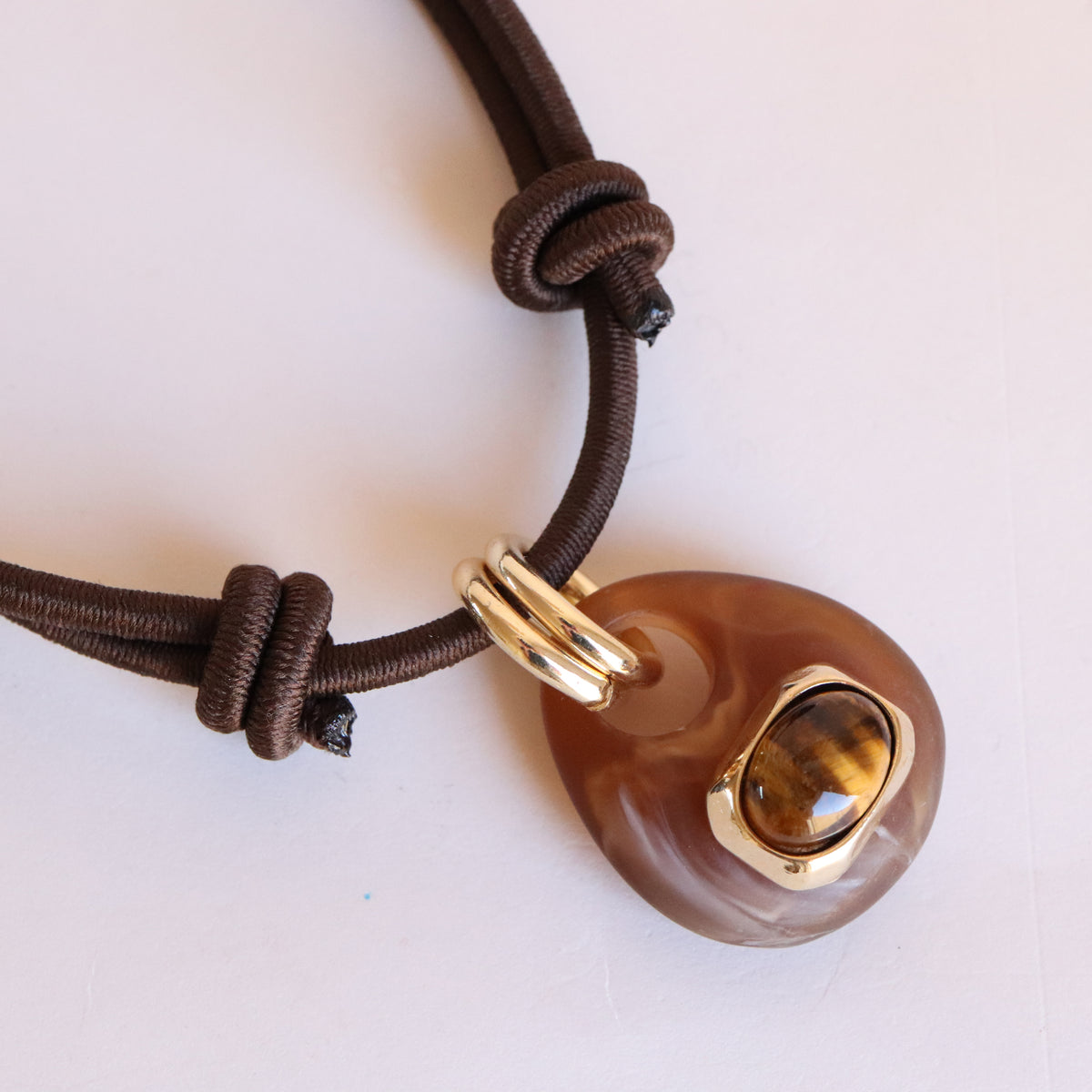 Detalle del collar corto Milu Sianna mármol marrón de Emolo, colgante veteado con piedra clara en engaste dorado y cordón marrón anudado