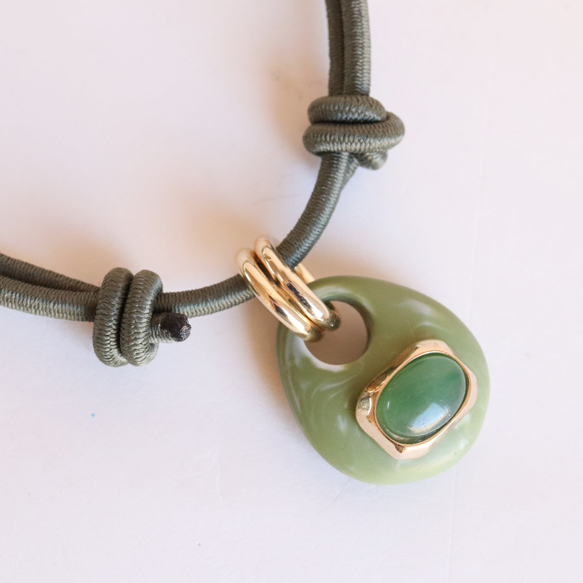 Detalle del collar corto Milu Sianna mármol verde de Emolo, colgante veteado con piedra verde agua en engaste dorado y cordón marrón anudado