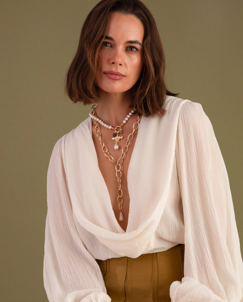 Detalle del collar Lyss de Emolo: la perla barroca y el acabado dorado de la cadena de latón