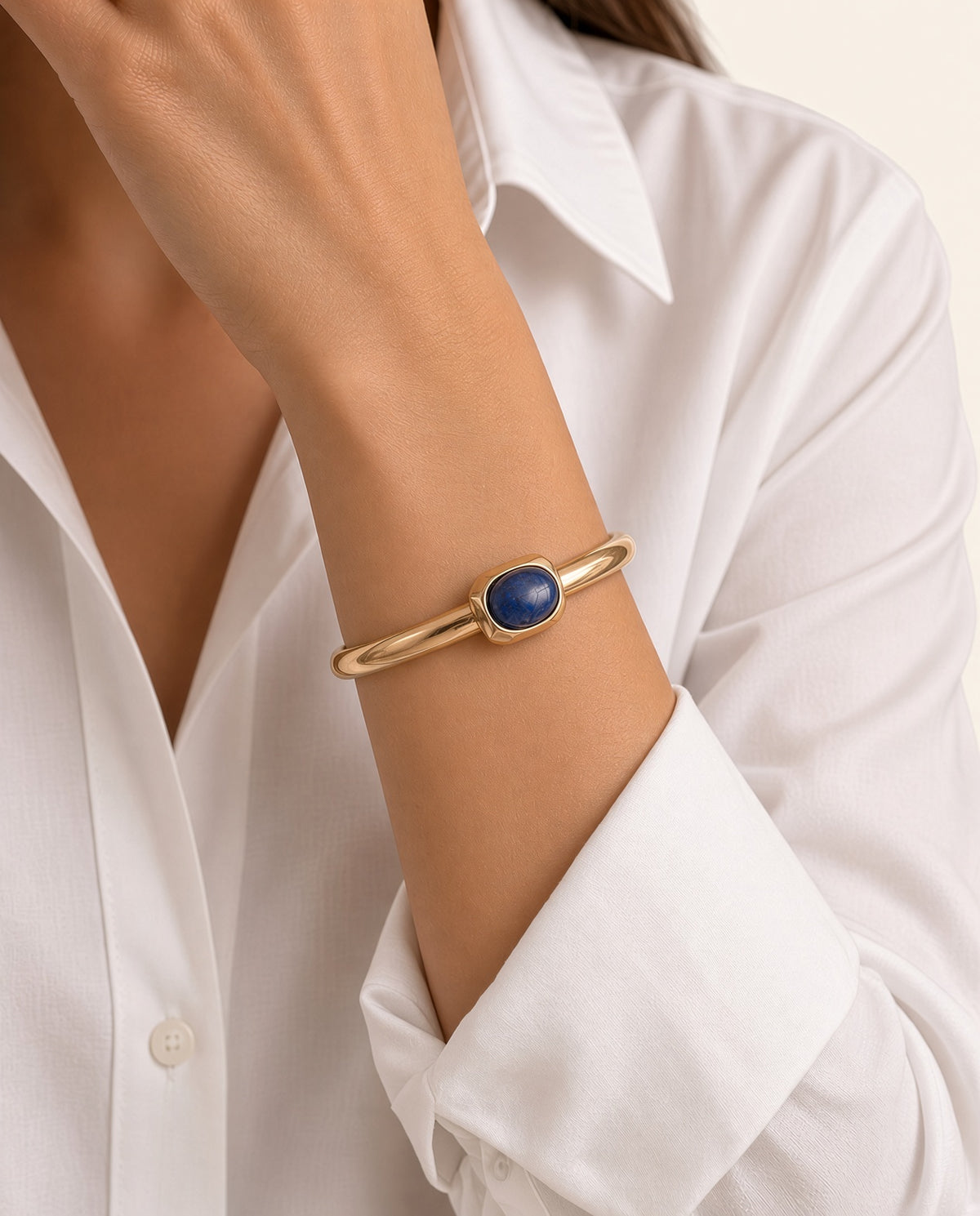 Modelo con el brazalete Luvo de Emolo en dorado con apatita azul, sobre camisa blanca