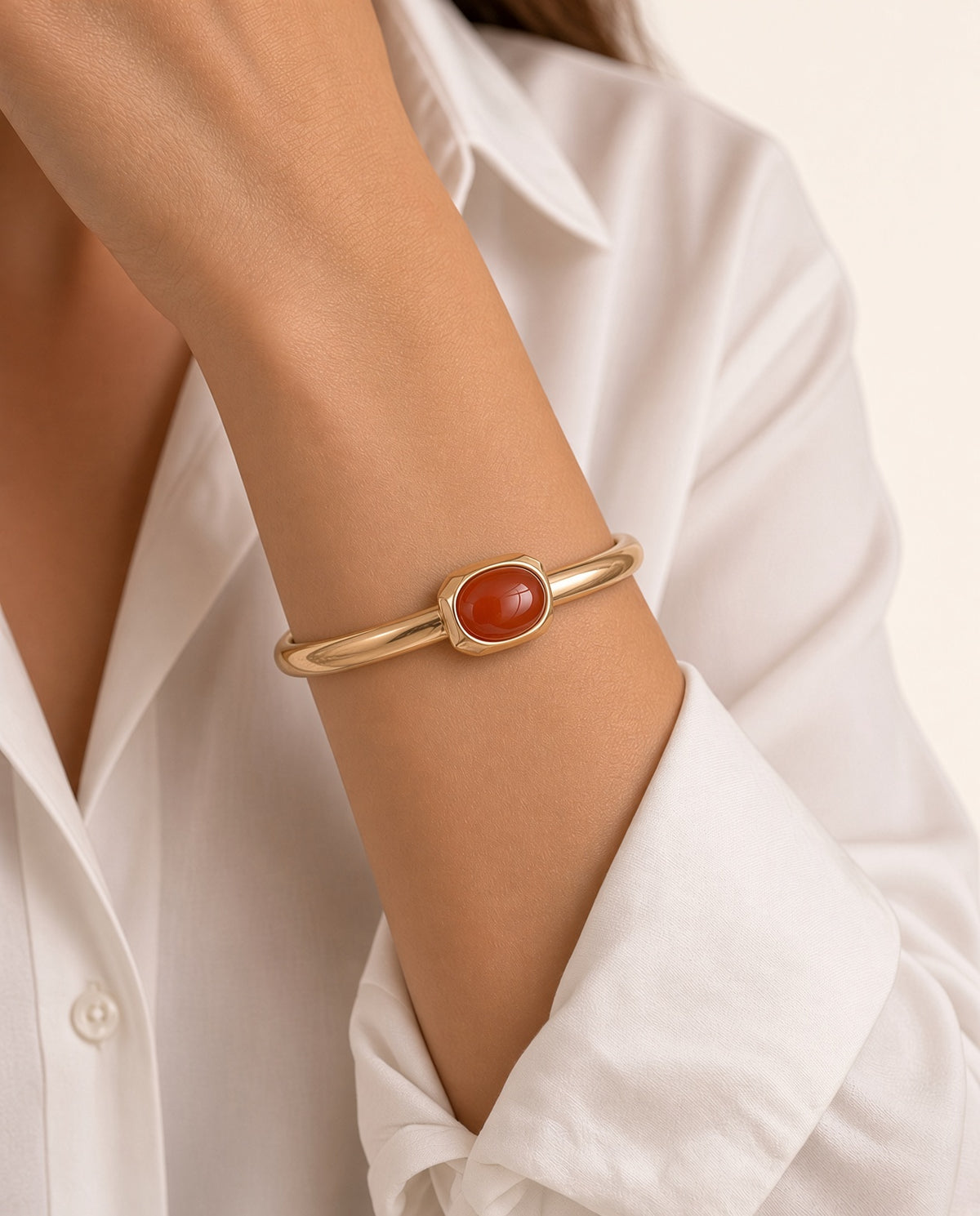 Modelo con el brazalete Luvo de Emolo en dorado con ágata miel, sobre camisa blanca