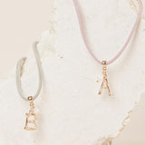 colgante de cordón con inicial dorada